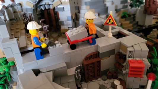 Ein Baustein wird auf die Mauer gebracht